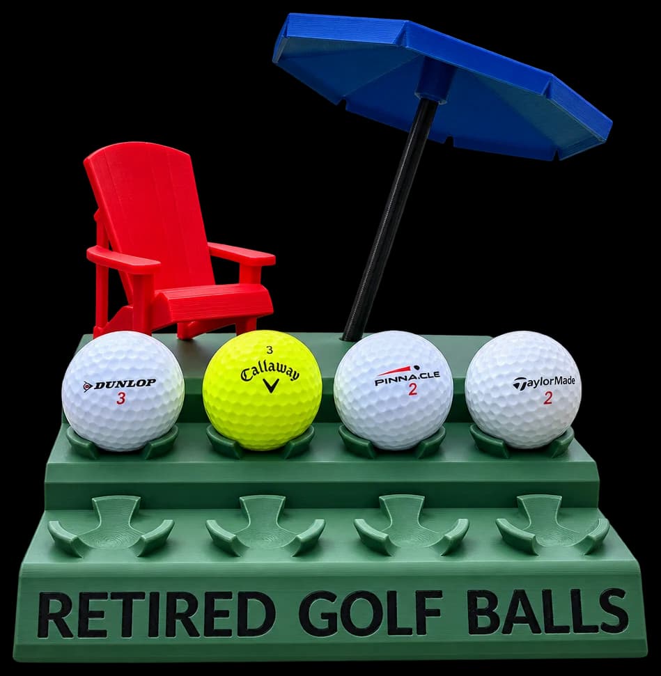 Green stepped stand reading Retired Golf Balls holding four balls, with a tiny red chair and blue umbrella