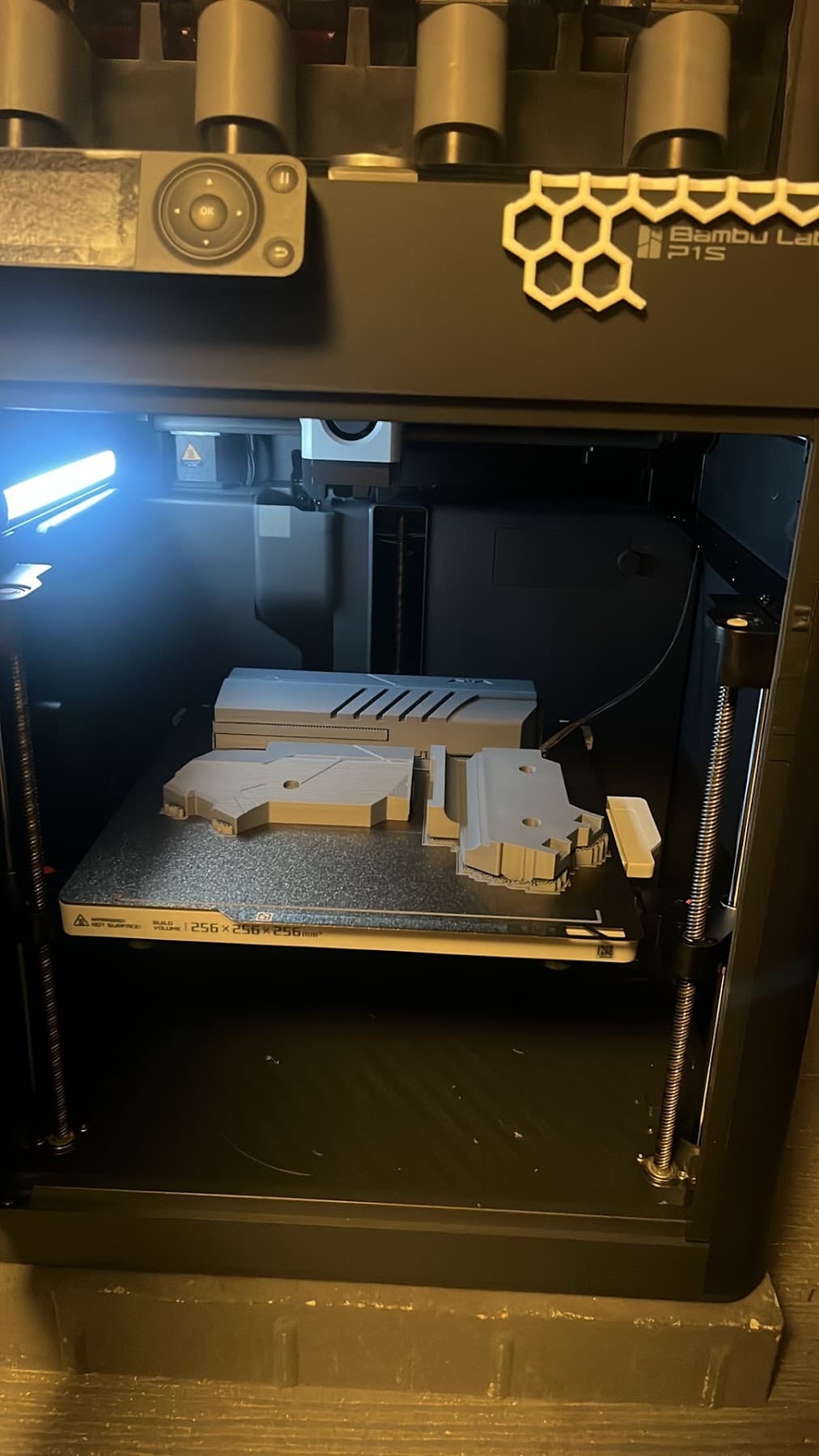 Grey parts mid-print on the build plate of a Bambu Lab P1S